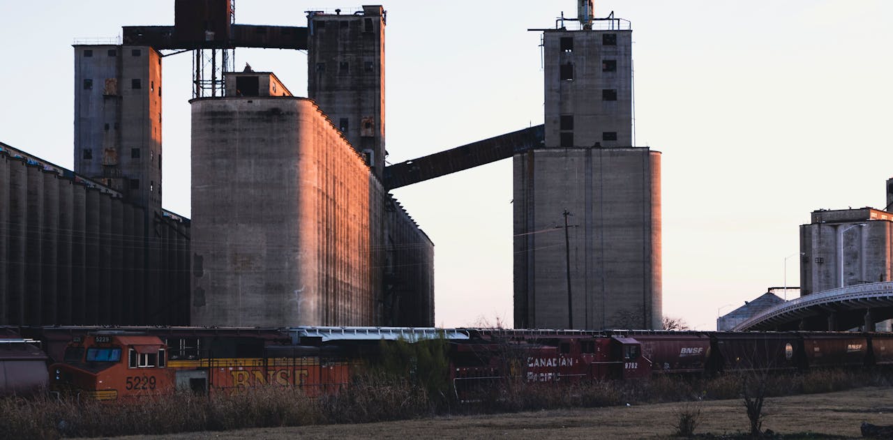 who-we-are Sunlit grain silos and freight trains in Fort Worth, Texas, highlighting industrial architecture.